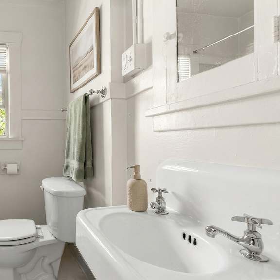 a white bathroom with a toilet, sink, and bathtub.