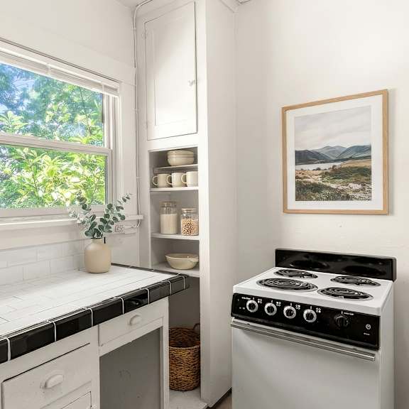 a small kitchen with a stove, sink, and window.