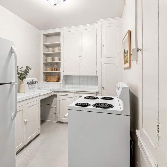a white kitchen with a refrigerator, stove, and cabinets.