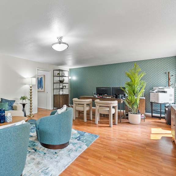 a living room with a blue chair and a painting on the wall.