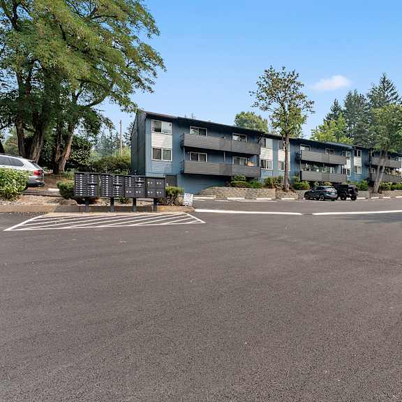 a parking lot with cars and a building in the background.