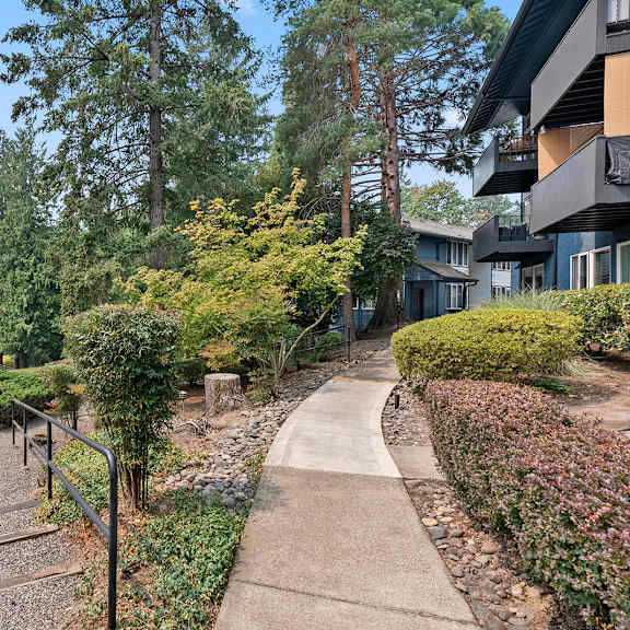 a pathway with a metal railing on the left side and a building on the right side.