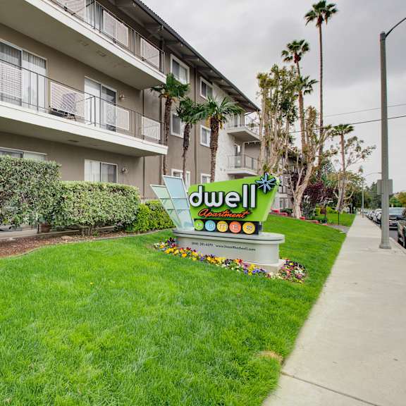 a lawn with a sign in front of an apartment building at dwell apartment homes, riverside, ca, 92507