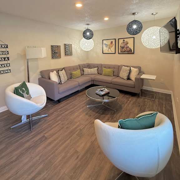 a living room with a grey couch, a white chair and a coffee table.
