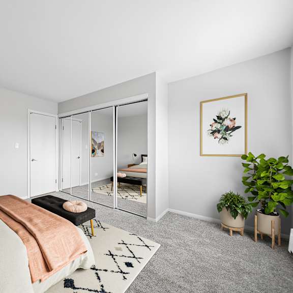 a bedroom with a bed, a couch, a rug, and a plant.