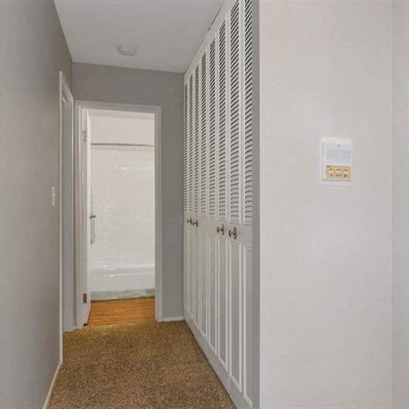 a hallway with a closet and a door to a bathroom at renew aurora, aurora, illinois