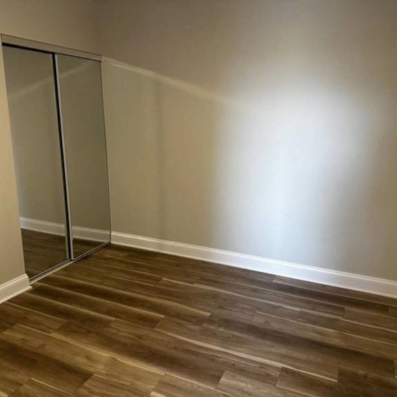 a room with a wooden floor and a mirrored closet at evelyn apartments, oak park