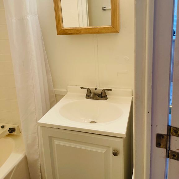 a white sink in a small bathroom with a wooden framed mirror above it.