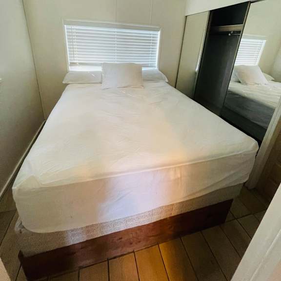 a bed with white bedspread and pillows in a room.
