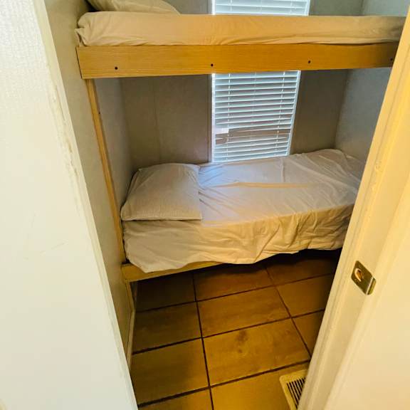 a small room with a bunk bed and a window with blinds.