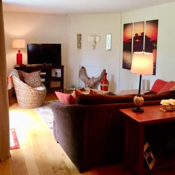a living room with a red couch and a wooden floor at little eagle bay apartments, burlington, 05408