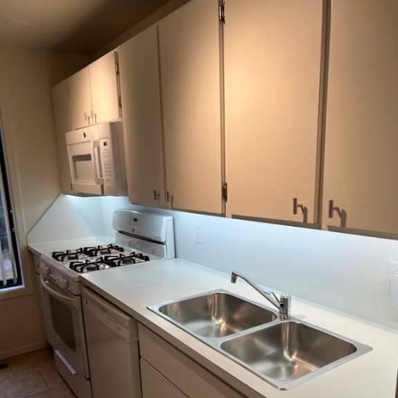 a kitchen with a stove, sink, and cabinets at little eagle bay apartments, burlington, vt