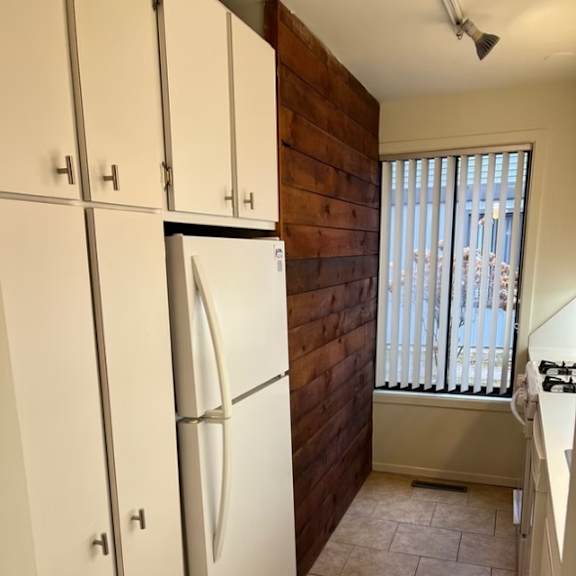 a kitchen with a white fridge and cabinets and accent wall at little eagle bay apartments, burlington, vt