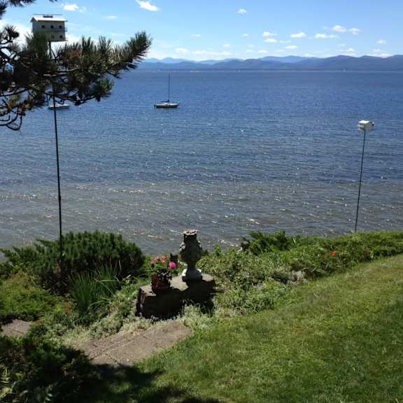 a view of a lake with a boat and a house in the distance.