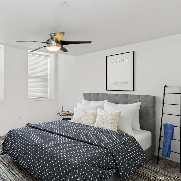 a bedroom with a bed, chair, and a ceiling fan.