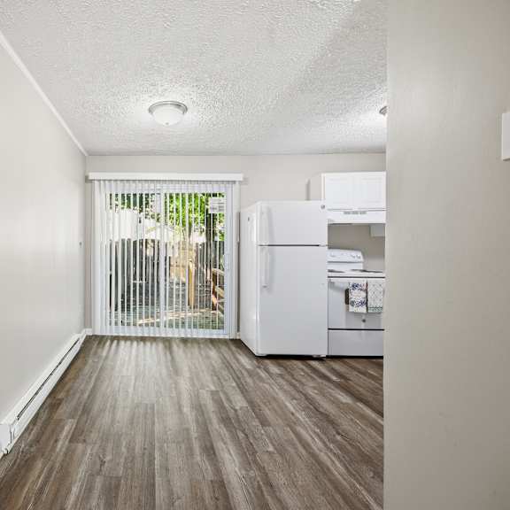a kitchen with white appliances and wooden floors.