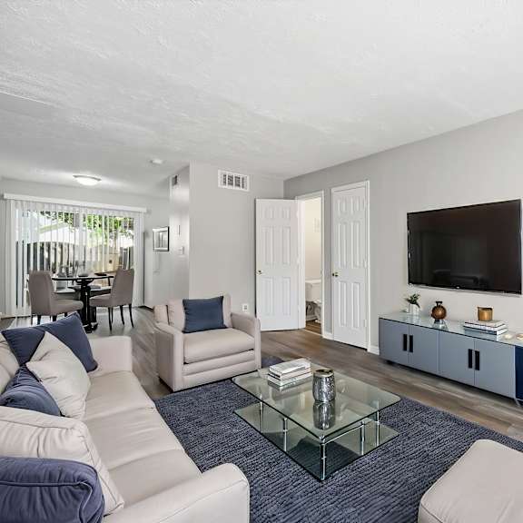 a living room with a glass coffee table and a white couch.
