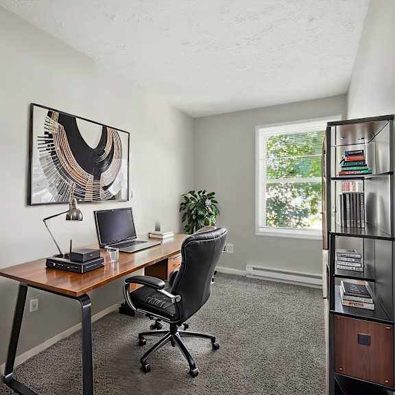 a room with a desk, chair, and bookshelf.