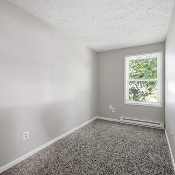 a room with a window and a carpeted floor.
