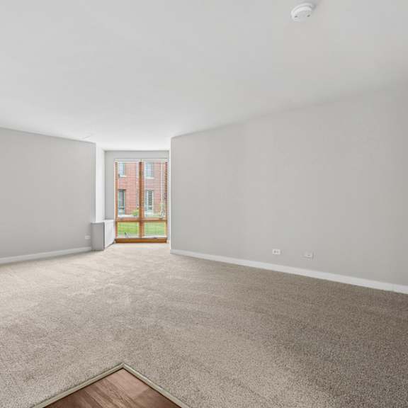 a room with a carpeted floor and a doorway leading to a balcony.
