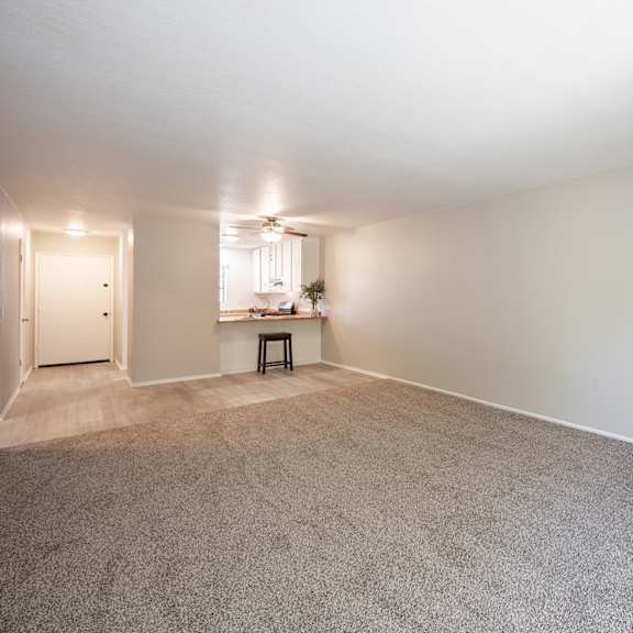 an empty living room with a fireplace and a kitchen at oak park apartments, solvang, ca