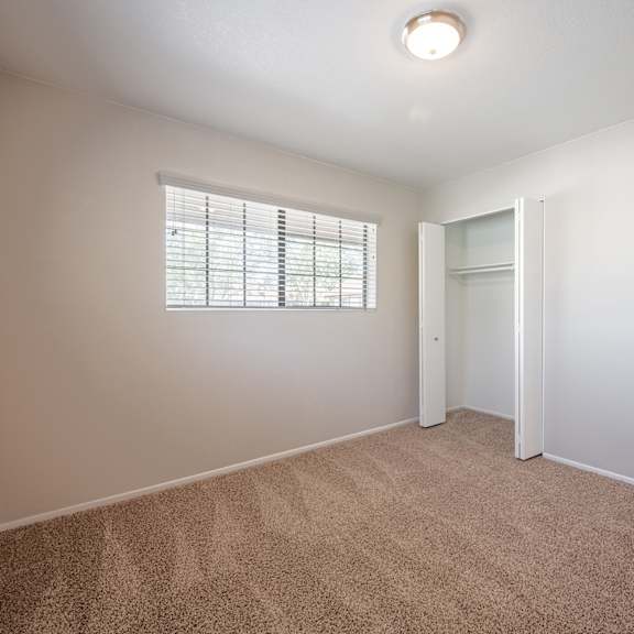 an empty bedroom with a window and a door to a closet  at oak park apartments, california