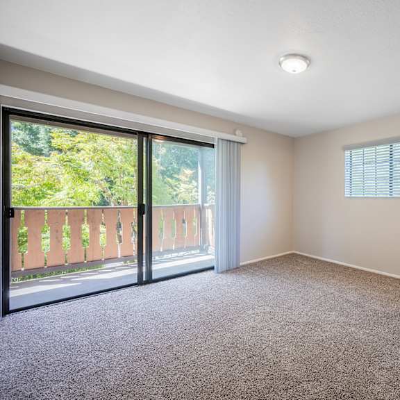 an empty living room with a sliding glass door to a balcony at oak park apartments, solvang, ca