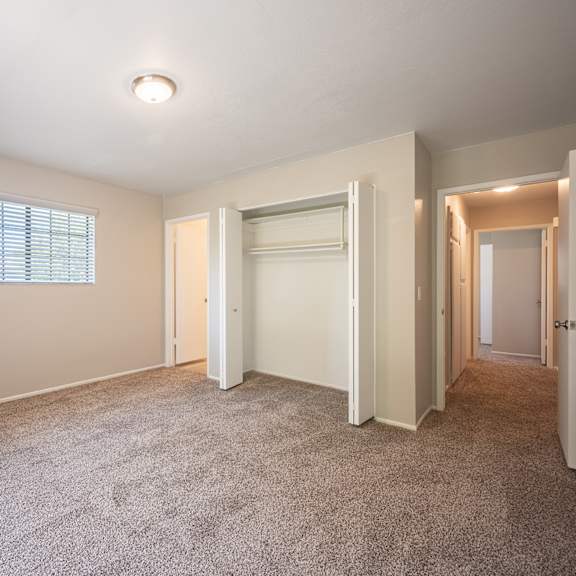 an empty bedroom with carpet and a door to a closet  at oak park apartments, california, 93463