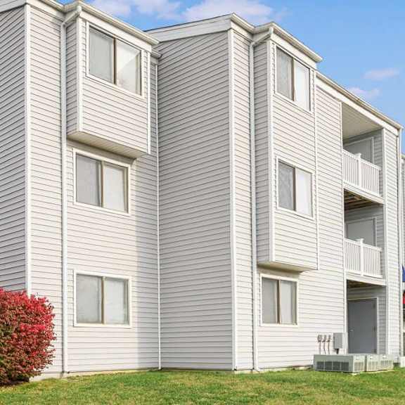 a white apartment building with a red shrub in front of it at renew odenton, maryland, 21113