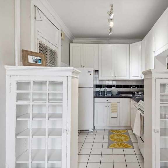 a white kitchen with white cabinets and a yellow rug at the bryant at oak park i & ii, oak park