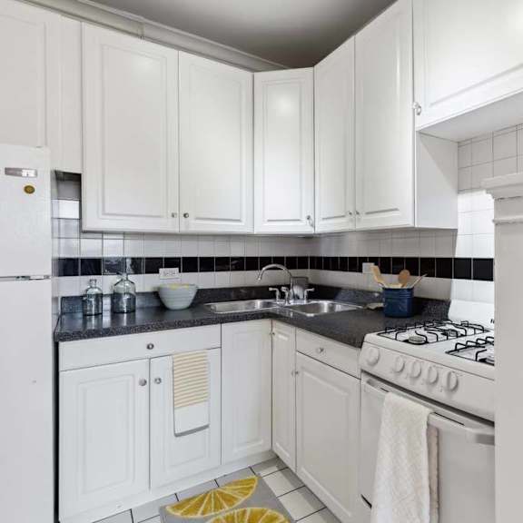 a white kitchen with white appliances and white cabinets at the bryant at oak park i & ii, illinois
