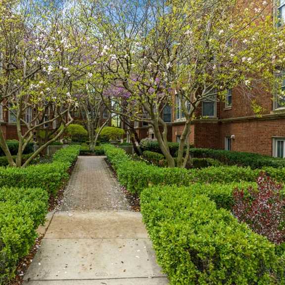 a sidewalk in front of a building with trees and hedges at the bryant at oak park i & ii, oak park, il 60302