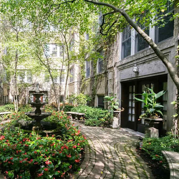 a courtyard with a fountain and flowers in front of a building at the bryant at oak park i & ii, oak park