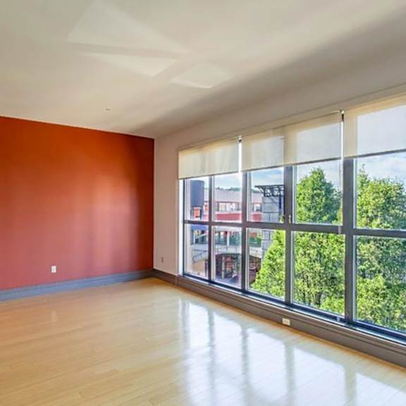 an empty room with a large window and hardwood floors at flats at southside, pittsburgh pennsylvania