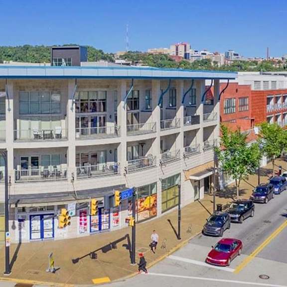 a large building with a blue roof on a city street at flats at southside, pittsburgh, 15203