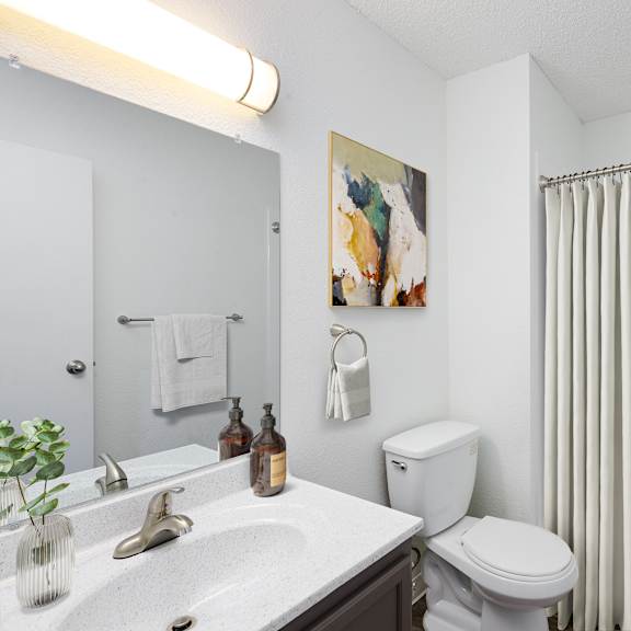 a white bathroom with a toilet, sink, and shower.
