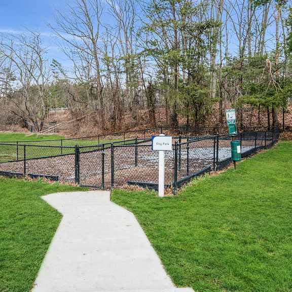 a sign in a park with a fence and a path.
