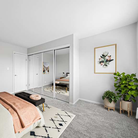 a bedroom with a bed, a couch, a rug, and a plant.