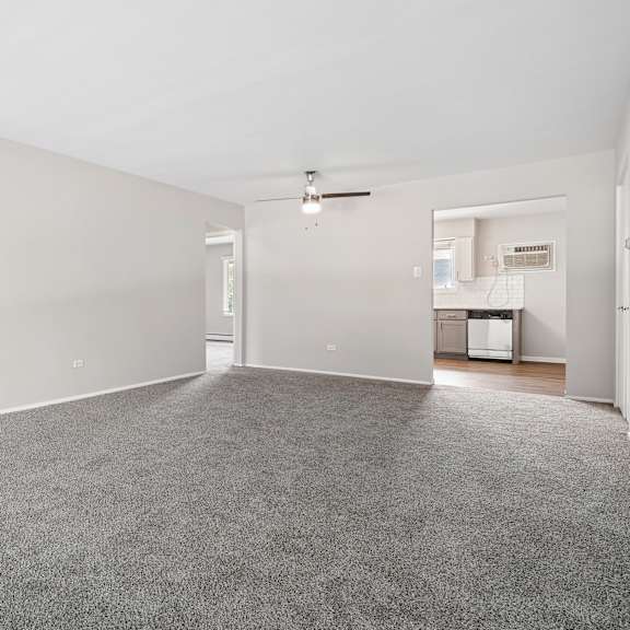 a spacious room with grey carpeting and white walls.
