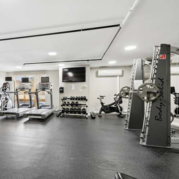 a spacious gym with a variety of equipment including treadmills, weights, and exercise bikes.