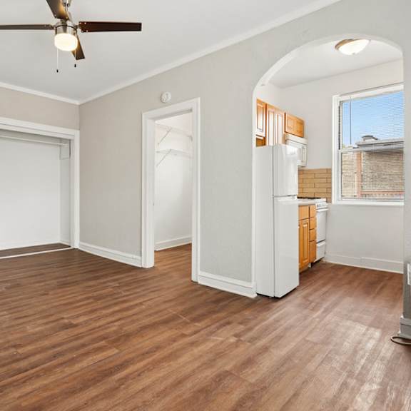 a room with a ceiling fan and wooden flooring.