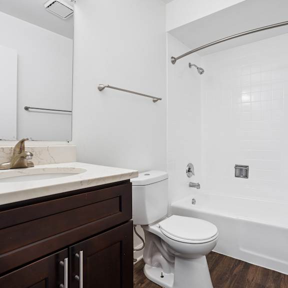 a white bathroom with a toilet, sink, and shower.
