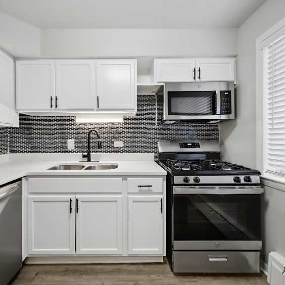 a kitchen with white cabinets and a black and white tiled backsplash.