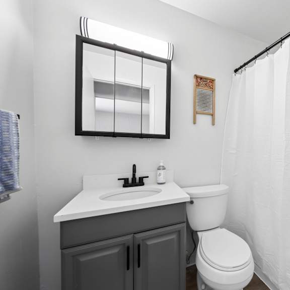 a white bathroom with a toilet, sink, and shower curtain.