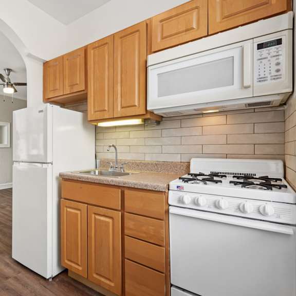 a kitchen with a white refrigerator, a white stove, and wooden cabinets.