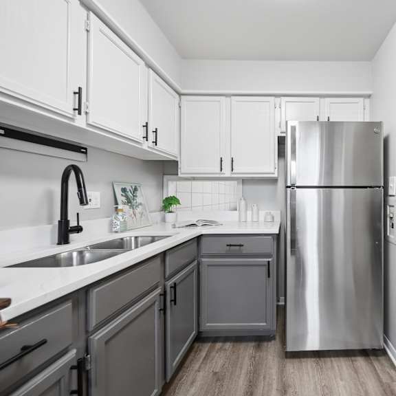 a modern kitchen with a stainless steel refrigerator and wooden flooring.