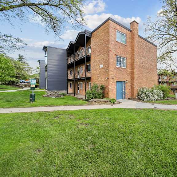 a large brick building with a blue door is surrounded by a grassy area and other buildings.