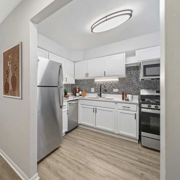 a modern kitchen with stainless steel appliances and wooden flooring.
