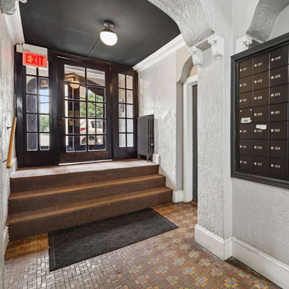 a wall of mailboxes is on the right side of a hallway.