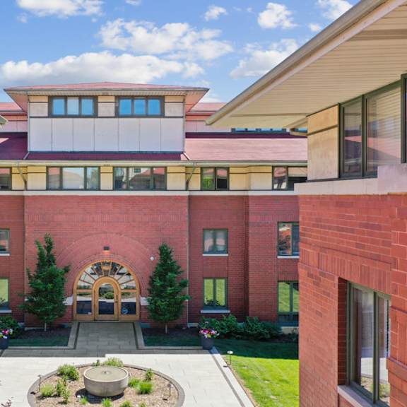 a red brick building with a circular entrance and a courtyard in front.